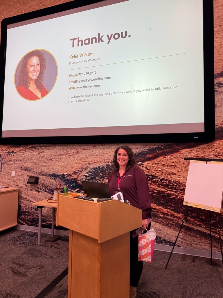 Kylie Wilson smiling at the podium after her breakout session, with her Thank you slide on the screen behind her