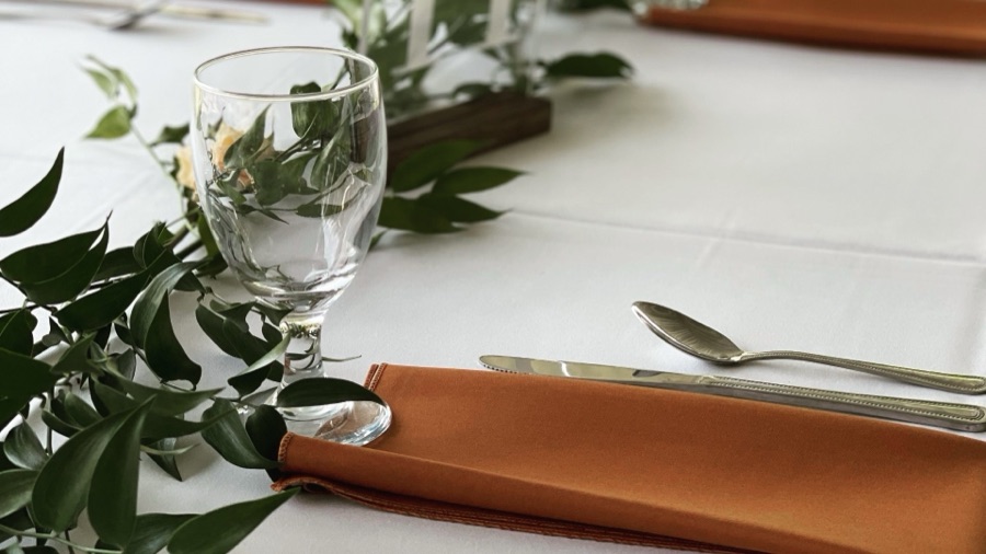 Table setting with fresh greenery and a copper napkin
