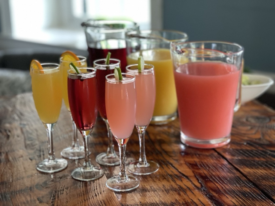 Mimosas and juice cocktails lined up on a wooden bar