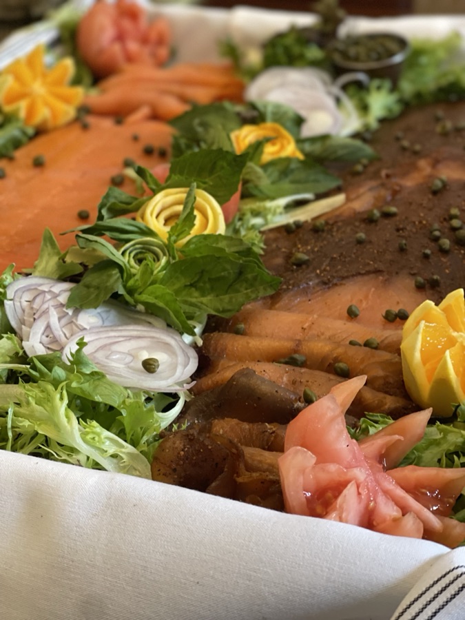 Smoked salmon platter with lemons, onions, and greens
