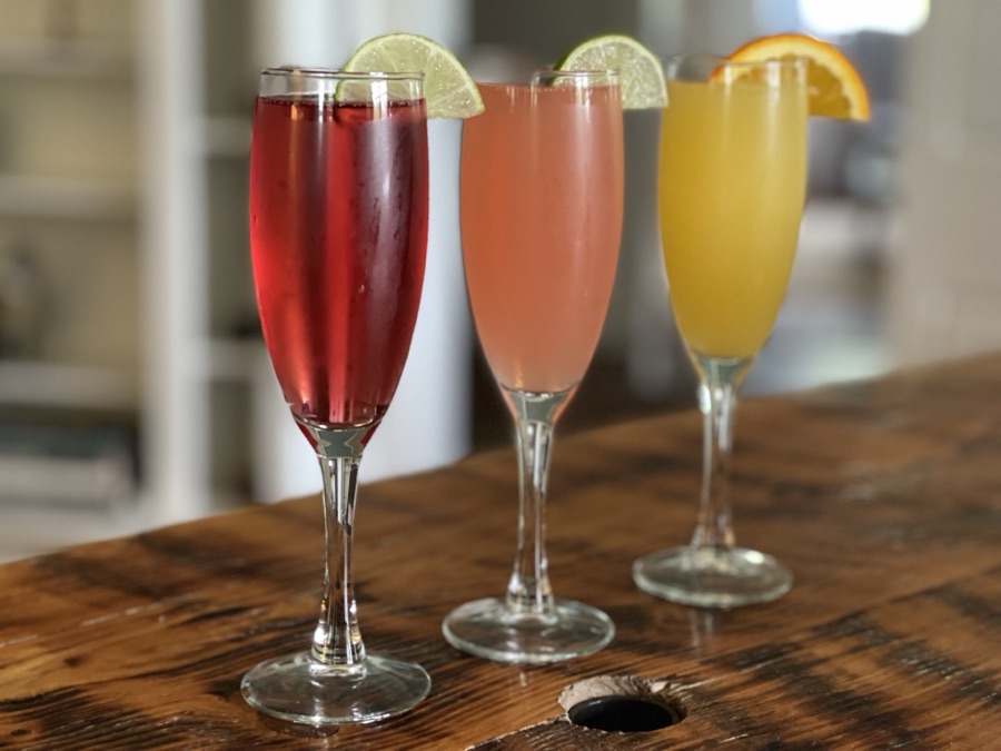 Three cocktails garnished with lime on a wooden bar