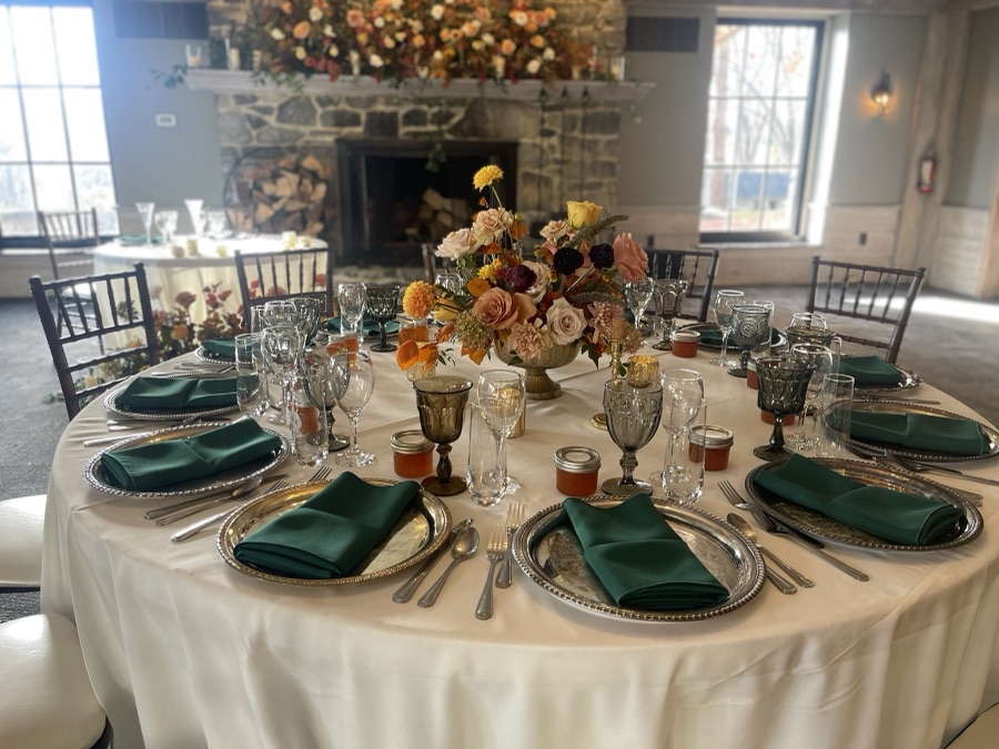 Fall table setting with emerald napkins, gold chargers, and autumn florals