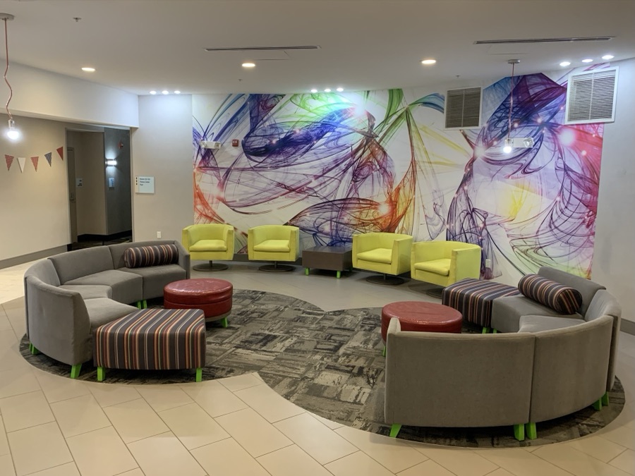 Colorful hotel lobby lounge with curved sofas and an abstract mural