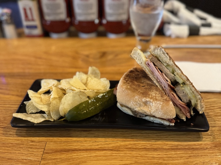 Pressed Cuban sandwich with chips and a pickle