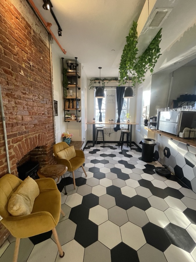 Coffee shop with exposed brick, hexagon tile floor, and mustard velvet chairs