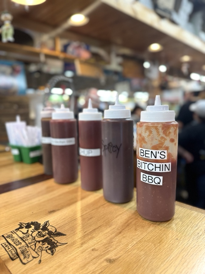 House barbecue sauce bottles lined up on a wooden counter