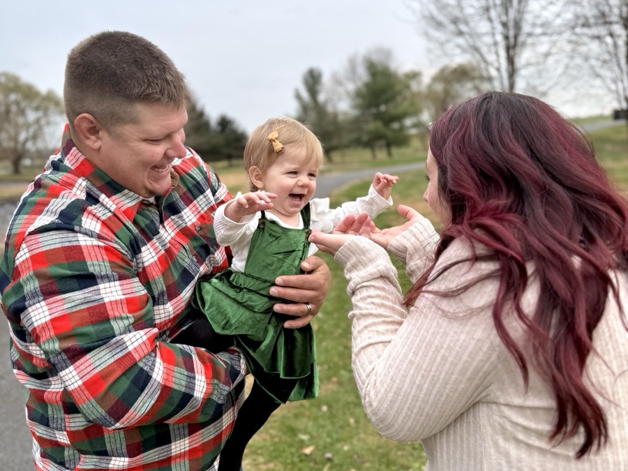 Family laughing together with their toddler outdoors