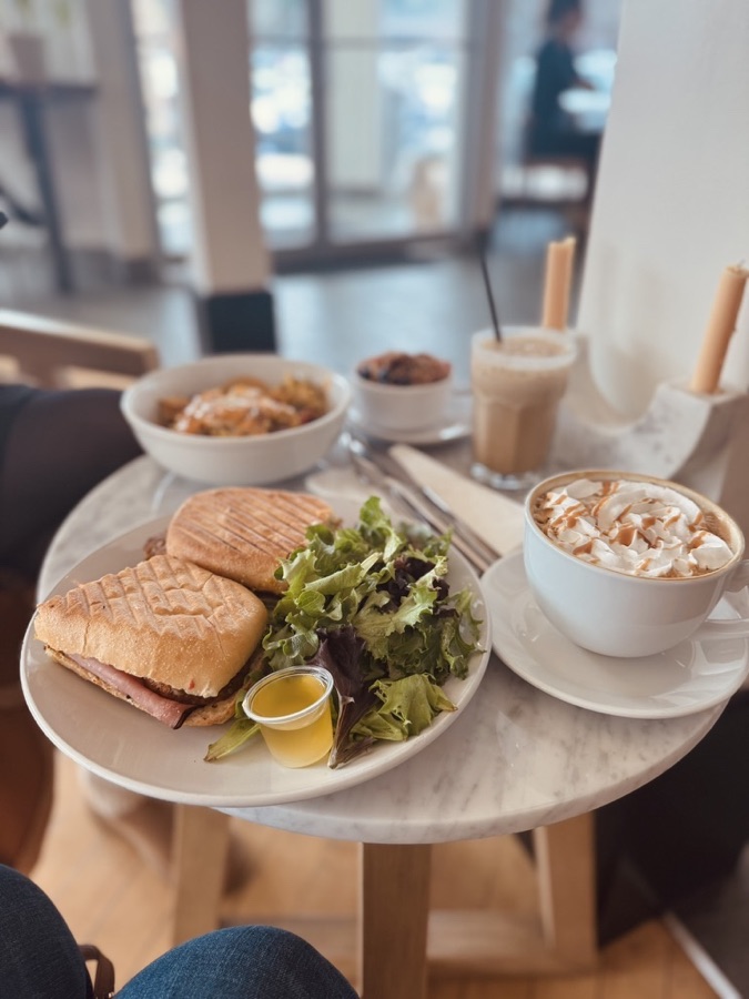 Cafe brunch with a pressed sandwich, salad, and lattes