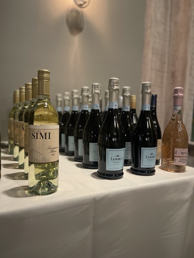 Wine and prosecco bottles lined up on a white tablecloth