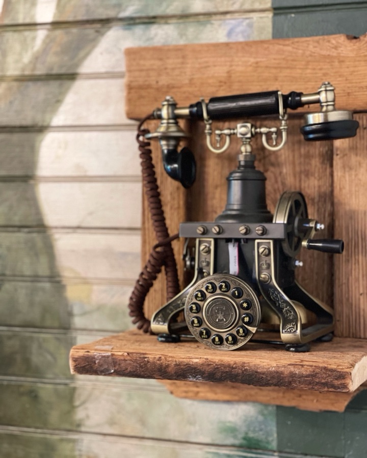 Vintage telephone mounted on a rustic wooden shelf